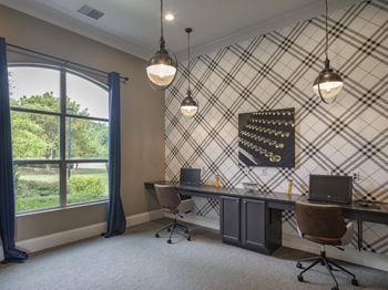 A room with a desk, chairs, and a window with curtains.